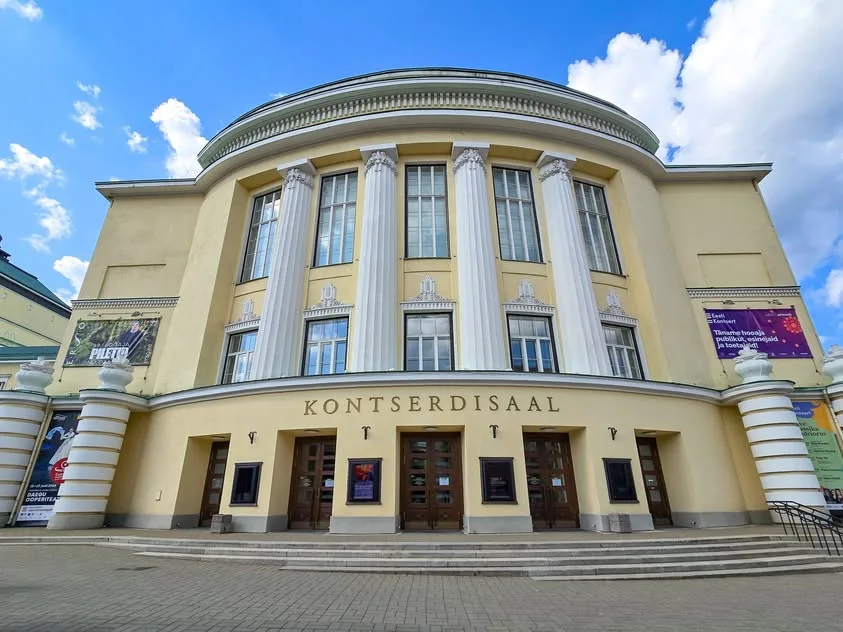 White columns and tall windows rise above steps at a yellow concert-hall facade.