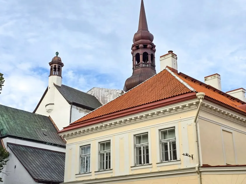 Copper-coloured spires and a red tiled roof rise above pale walls.
