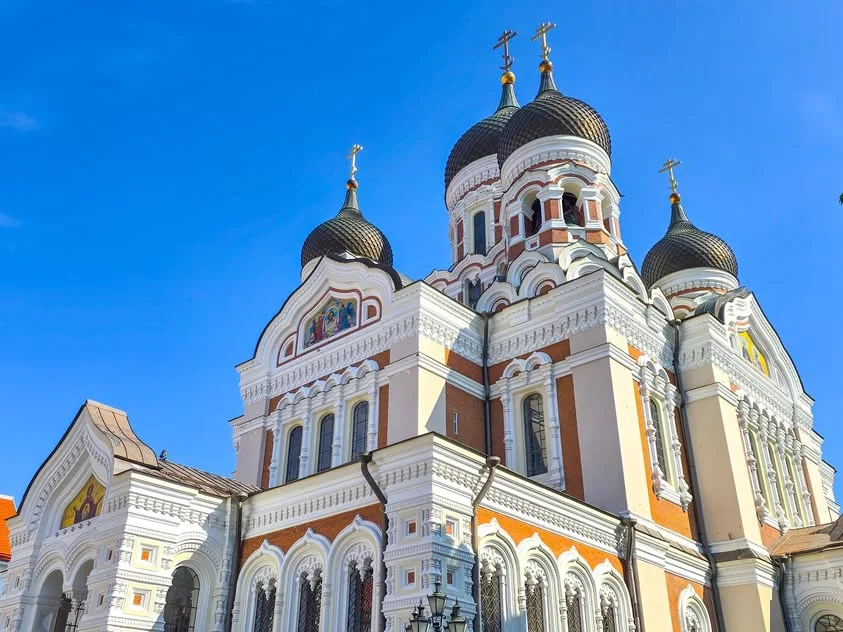 Dark onion-shaped domes and gold crosses rise above an ornate white and red church.