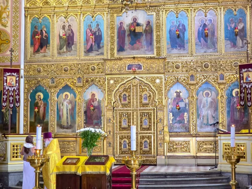 A gilded church screen displays painted icons above candle stands.