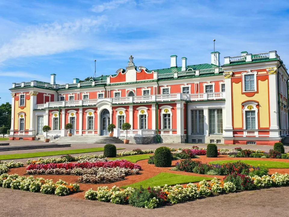 The red, yellow and white façade of Kadriorg Palace faces patterned flower beds and clipped shrubs.