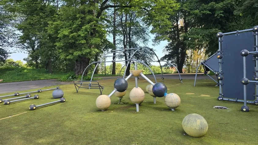 Metal bars and cream and blue spheres form a playground structure.