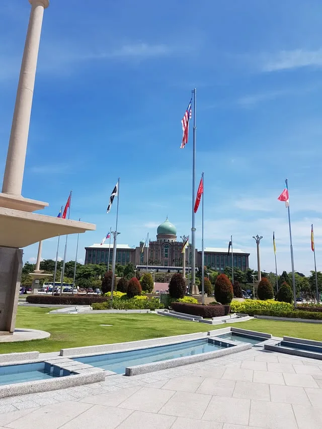 Flags, planted beds and a low water feature stand before the green-domed Perdana Putra building.