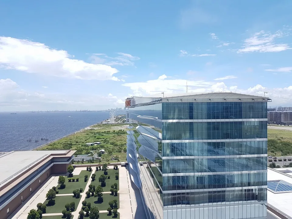 A glass-fronted Solaire building beside a planted terrace, with Manila Bay stretching into the distance.