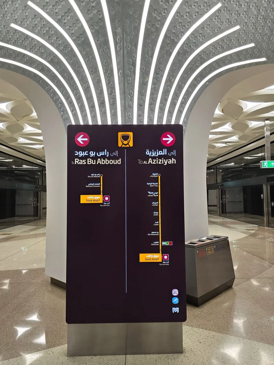 Direction signs for platforms hang beneath the sculptural ceiling of Souq Waqif metro station.