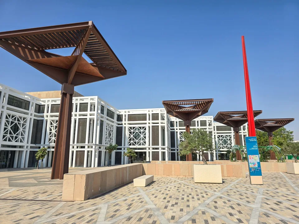 Angular shade structures and planted trees line a paved plaza in Education City.
