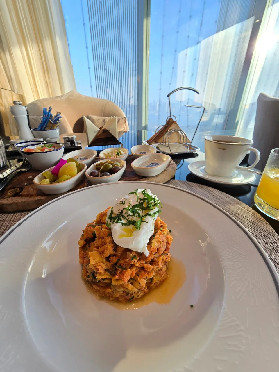 A plated egg dish with sauce and garnishes sits on the breakfast table.