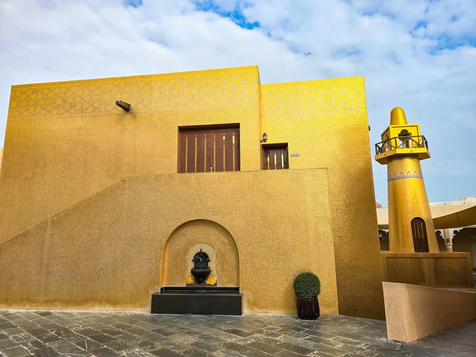 A mosque covered in gold-coloured tiles stands beneath a blue and cloudy sky at Katara Cultural Village.