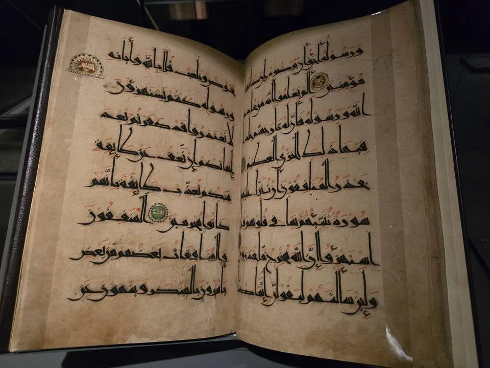 Broad angular Arabic script fills an open manuscript with small coloured roundels.