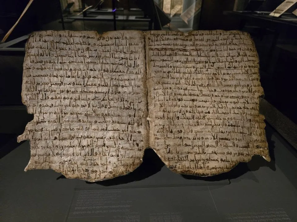 A pair of irregular-edged manuscript leaves displays rows of Arabic writing.