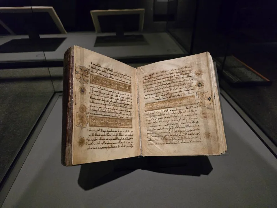 Fine Arabic calligraphy sits within rectangular gold borders across an open book.