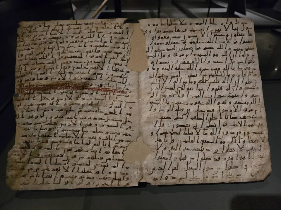 Two worn manuscript leaves carry dark Arabic script with missing areas near the centre.