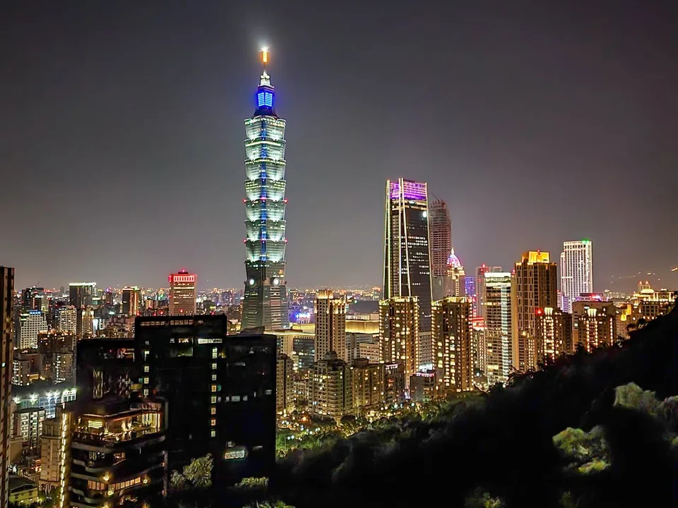 Taipei 101 shines above the illuminated city, seen from Elephant Mountain at night.