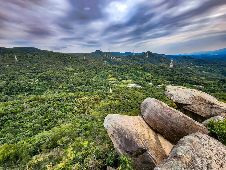 Large rounded boulders overlook green hills beneath streaked clouds.