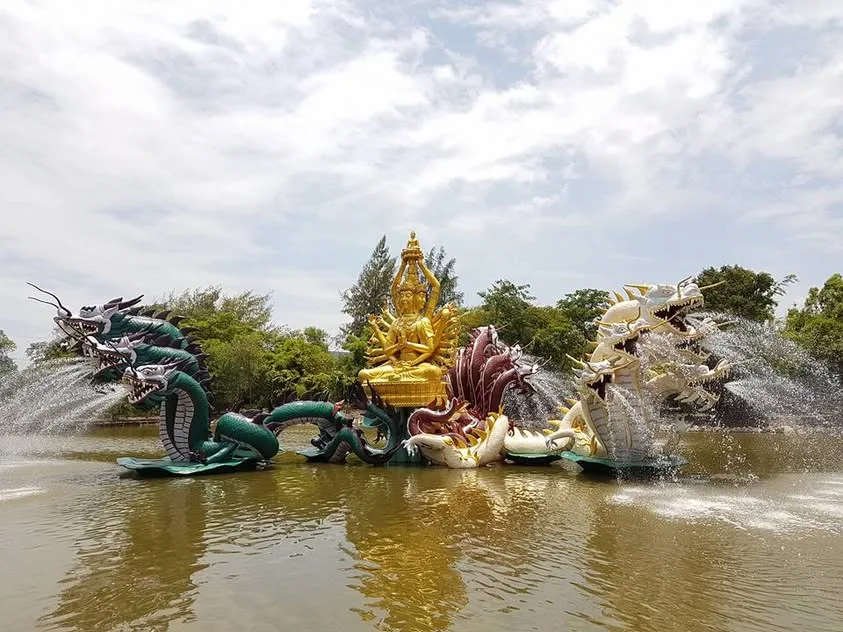 A sculptural fountain rises among serpent forms and carved figures.