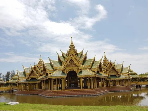 Green and gold roof tiers rise above a pavilion surrounded by water.