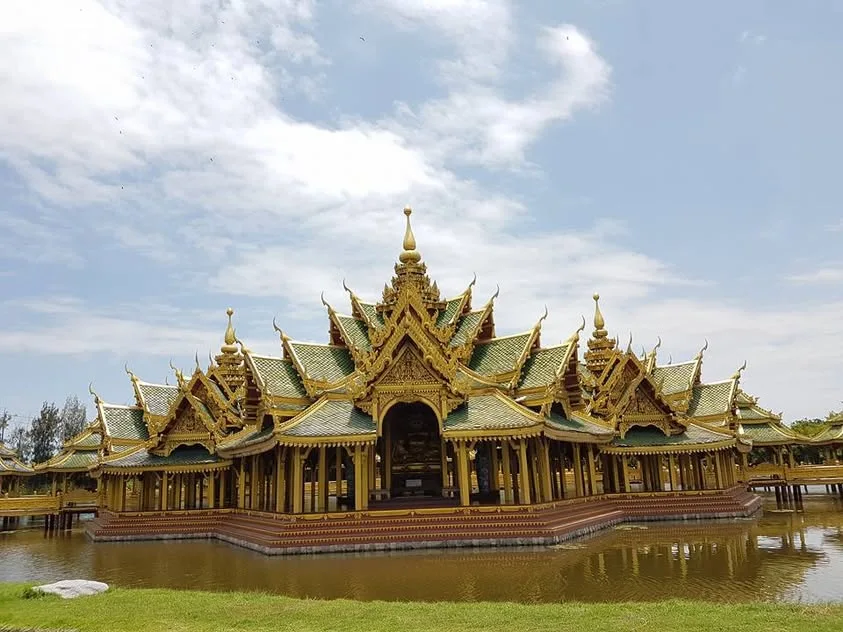 Green and gold roof tiers rise above a pavilion surrounded by water.